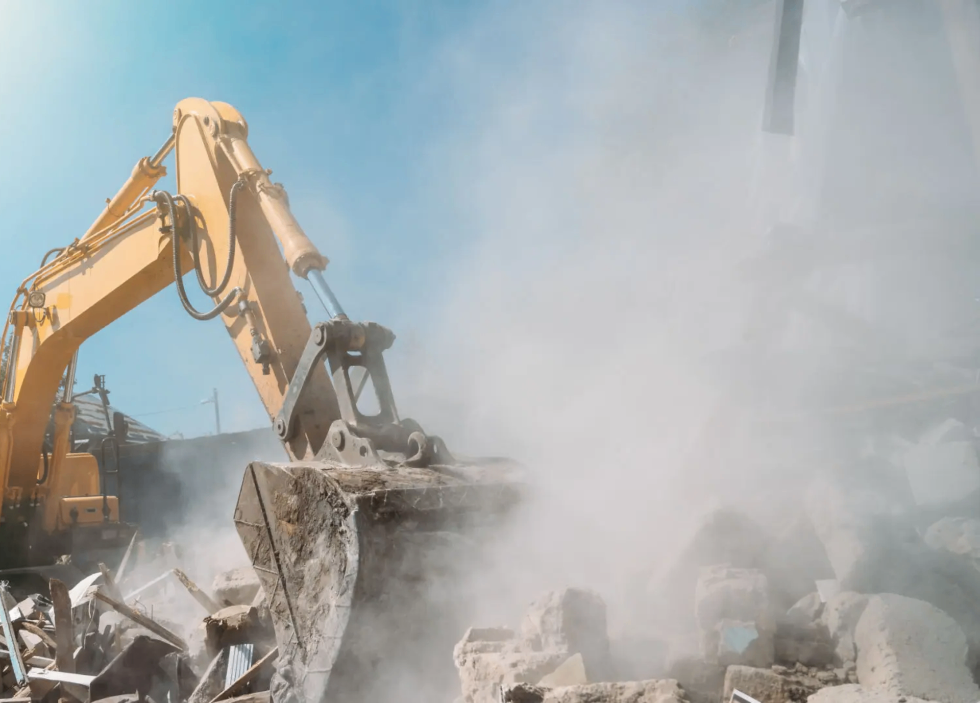 CAT excavator tearing down a residential home on a sunny Florida day with clear blue sky